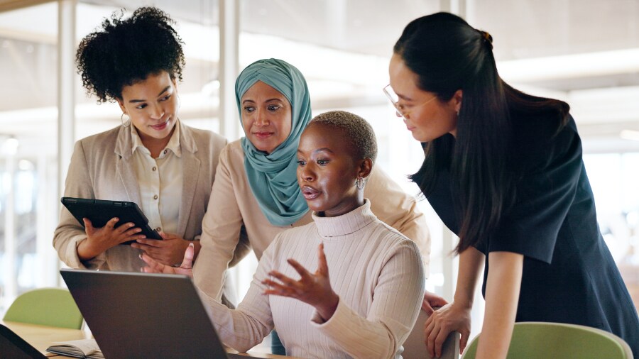 A group of women in front of a laptop and talking 