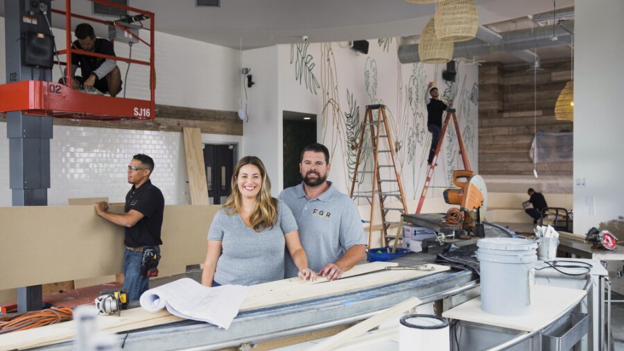 2 people standing in a kitchen being constructed.