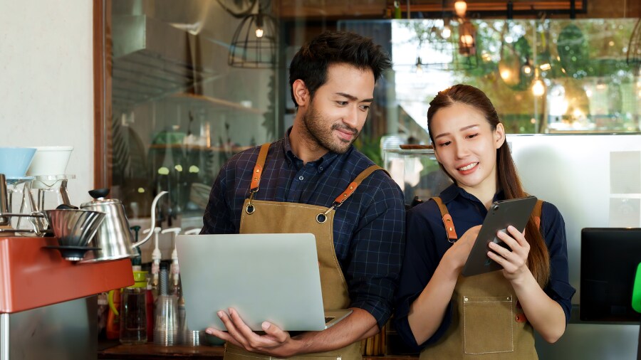 Two people standing next to each other and looking at tablets.