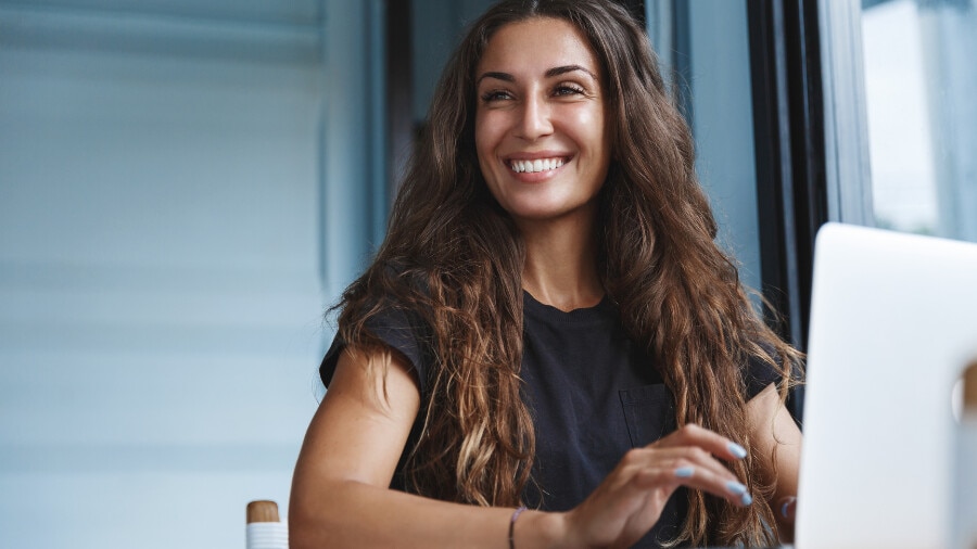 A person smiling while working on a laptop.