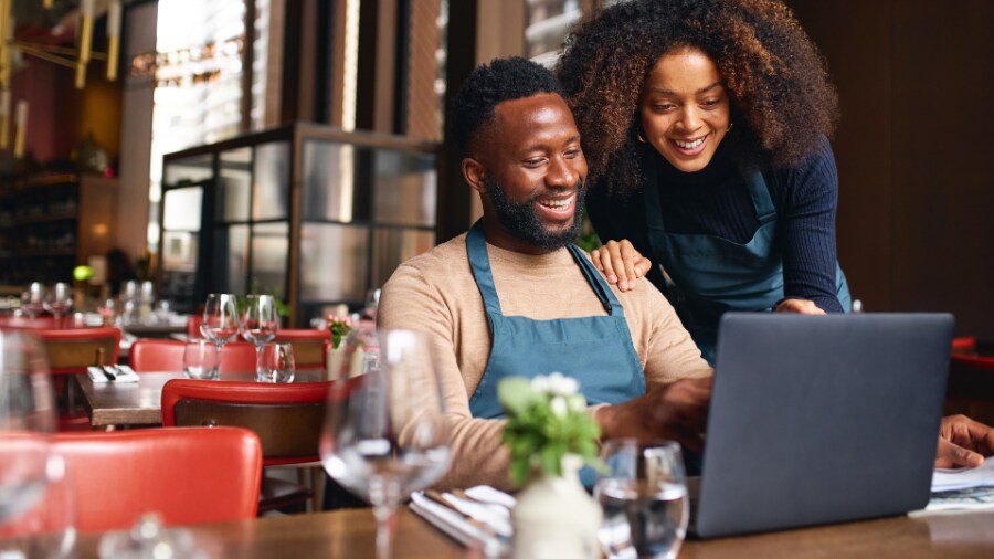 A man and a woman smiling at a laptop screen