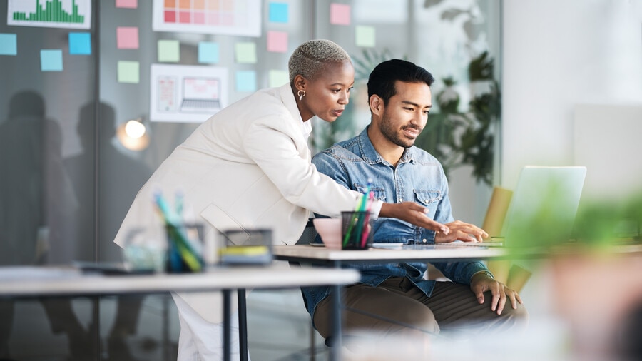 Two people sitting at a table looking at a laptop.