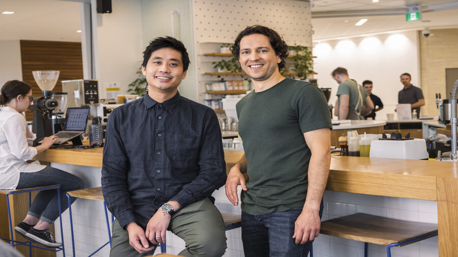 Two people are posing for a picture in a cafe.