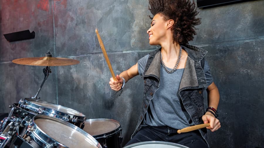 A woman flows with the beat while playing her drum set. 