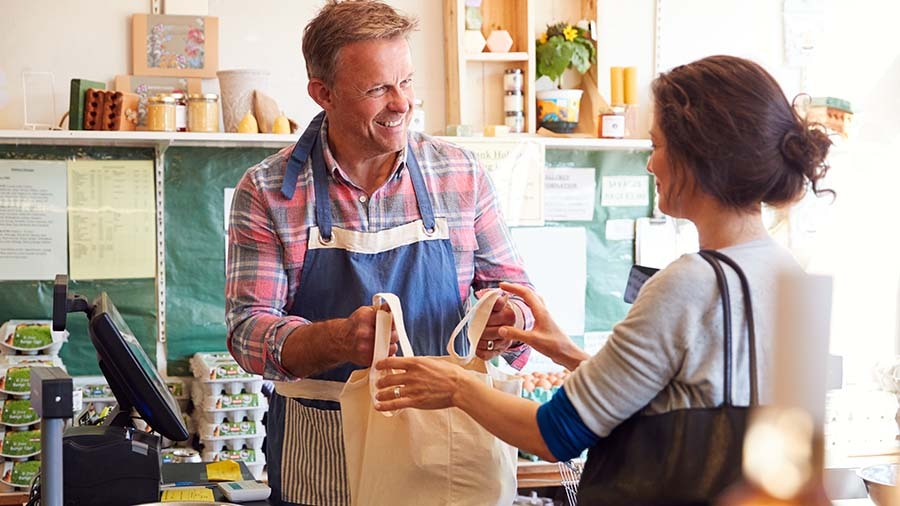 Small business owner handing grocery bag to customer