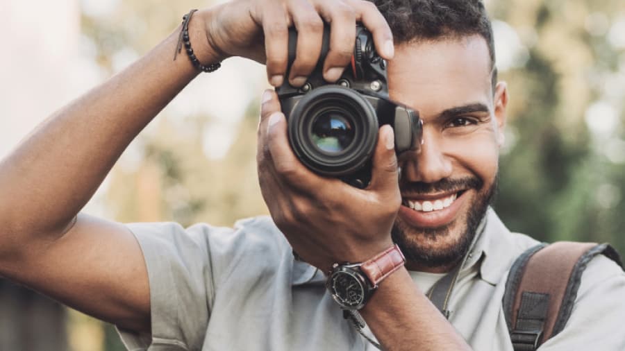 A photographer smiles while he aims his camera.