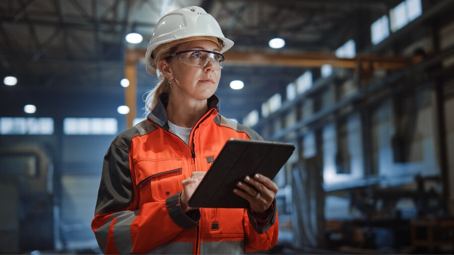 A person in a factory outfit holding a tablet.