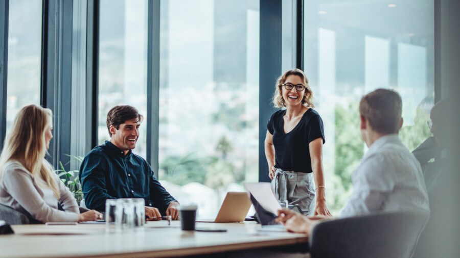 People sitting at a table with laptops and smiling.