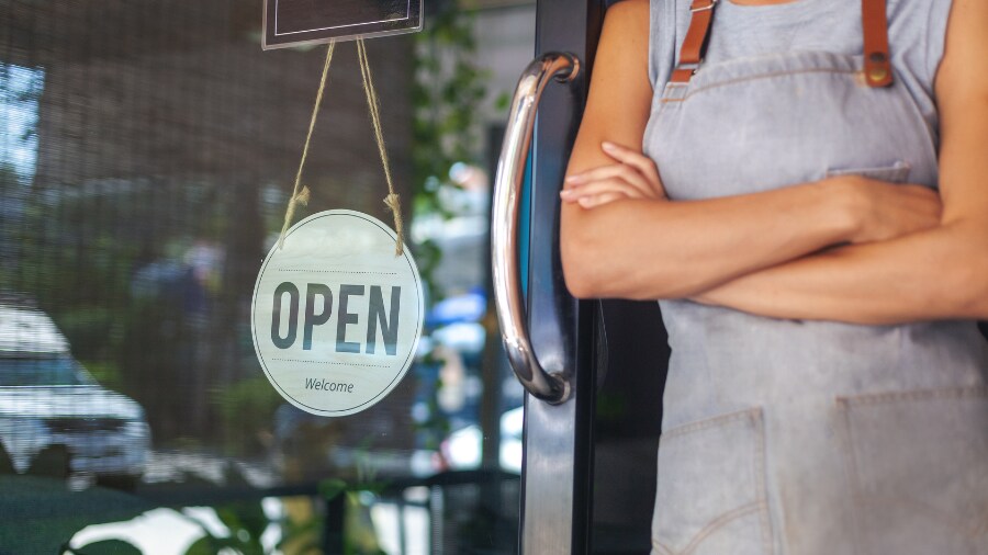 A person in a shop beside an open store sign 