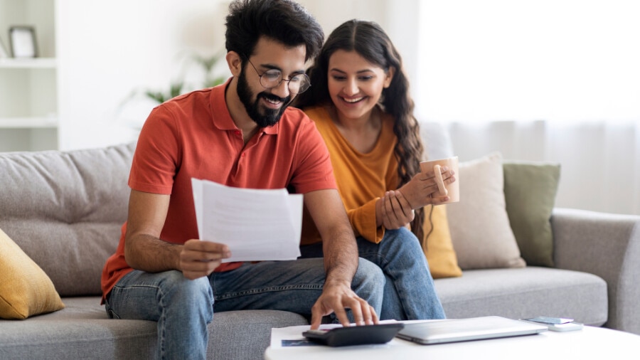 A man and woman sitting next to each other on a couch looking at documents 