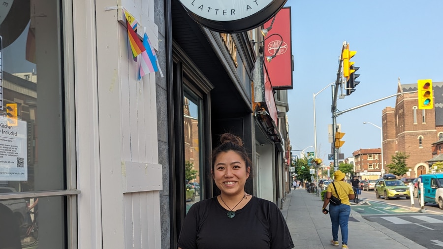 A woman standing on a sidewalk in front of a restaurant 