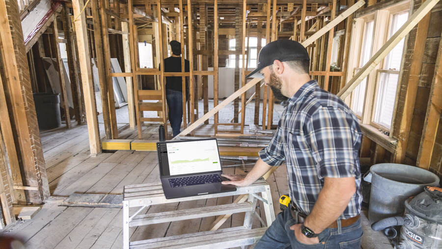 Shift Accessibility owner working on a laptop in a house under construction 