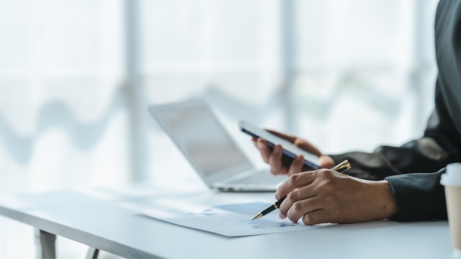 A person is typing  and looking at documents 