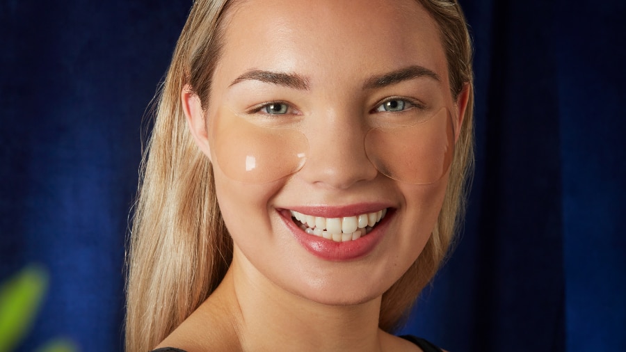 A woman smiling and wearing Three Ships Beauty Eye Mask 