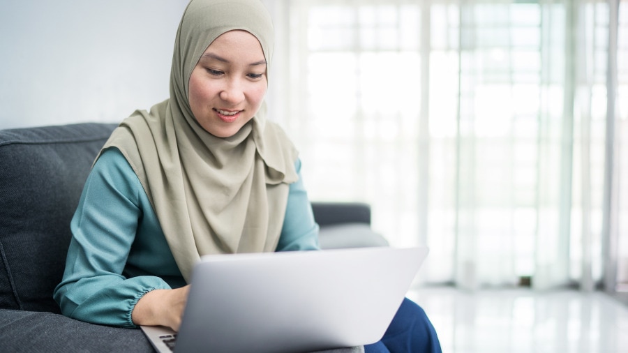 A woman sitting on a couch with a laptop.