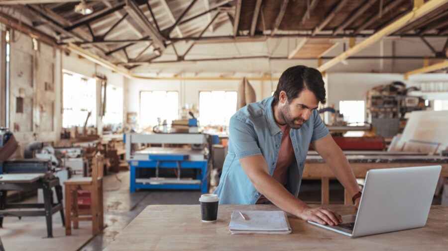 A man is working on a laptop in a construction site.