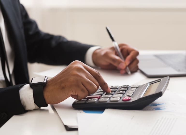 Homme utilisant un stylo et une calculatrice pour gérer la paie