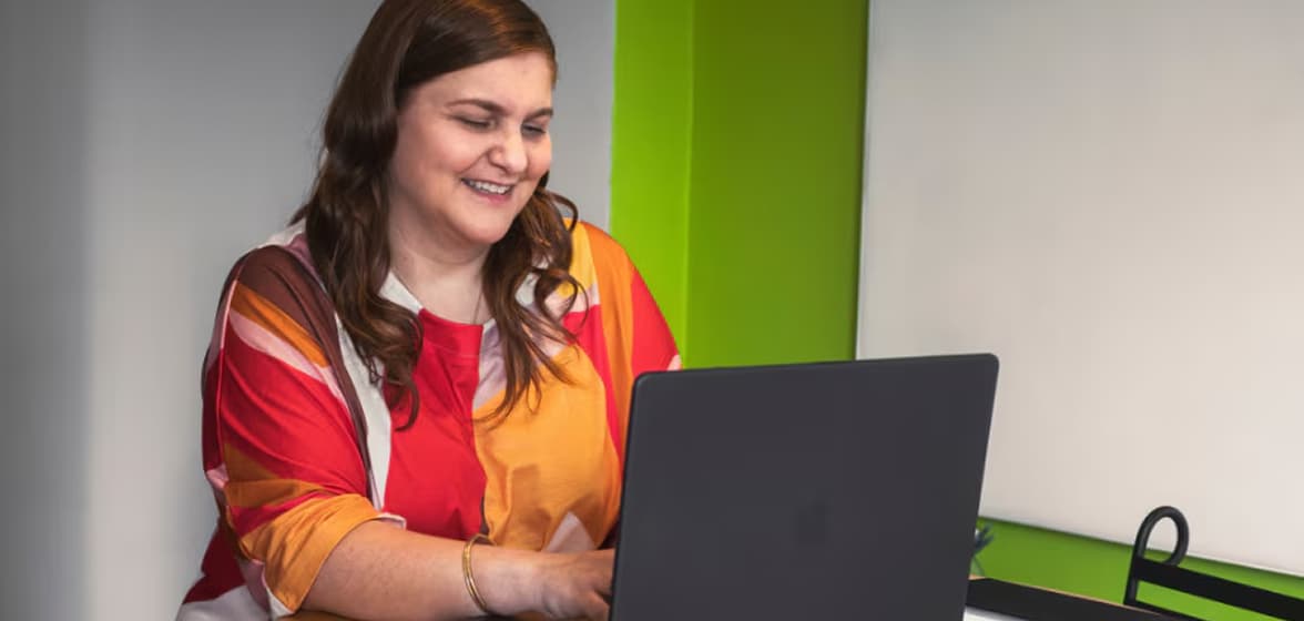 A person smiling and looking at a laptop.