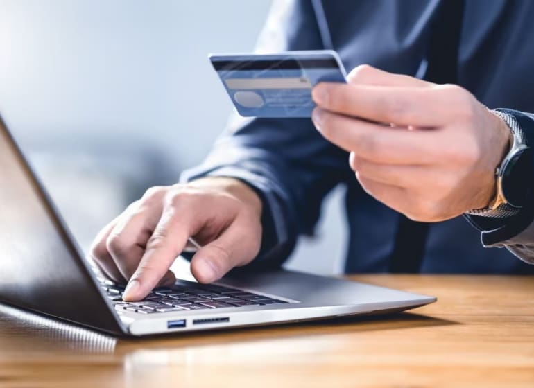 Homme effectuant un paiement par carte de crédit sur son ordinateur portable.