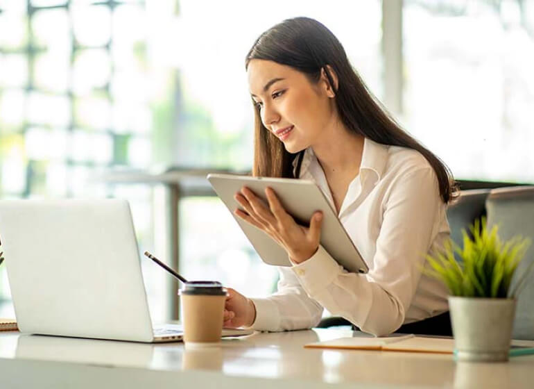 Office lady checking laptop, and holding tablet