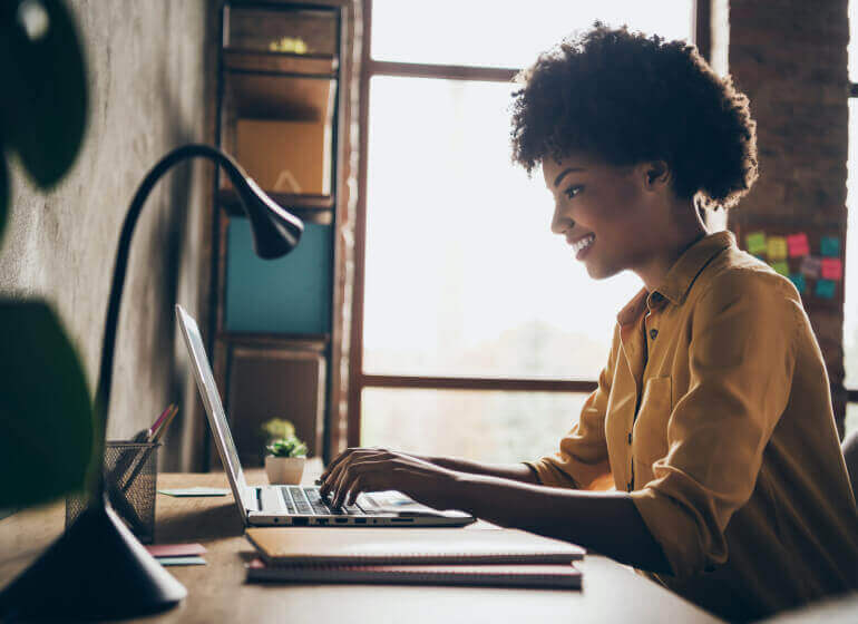 Woman working beside window on laptop