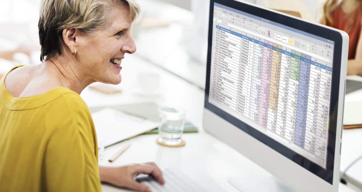 A person smiling while typing on a laptop.