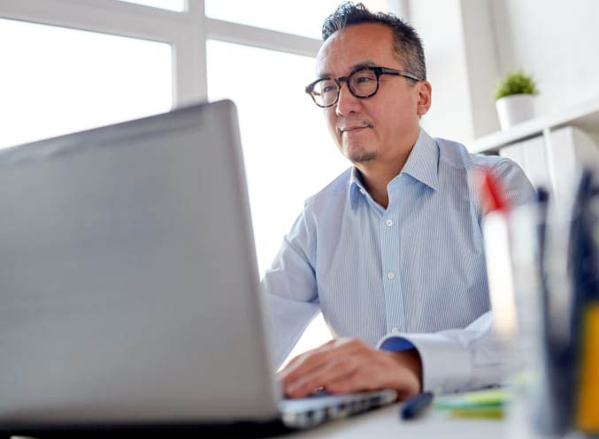 Un homme en chemise bleue travaille intensément sur son ordinateur portable
