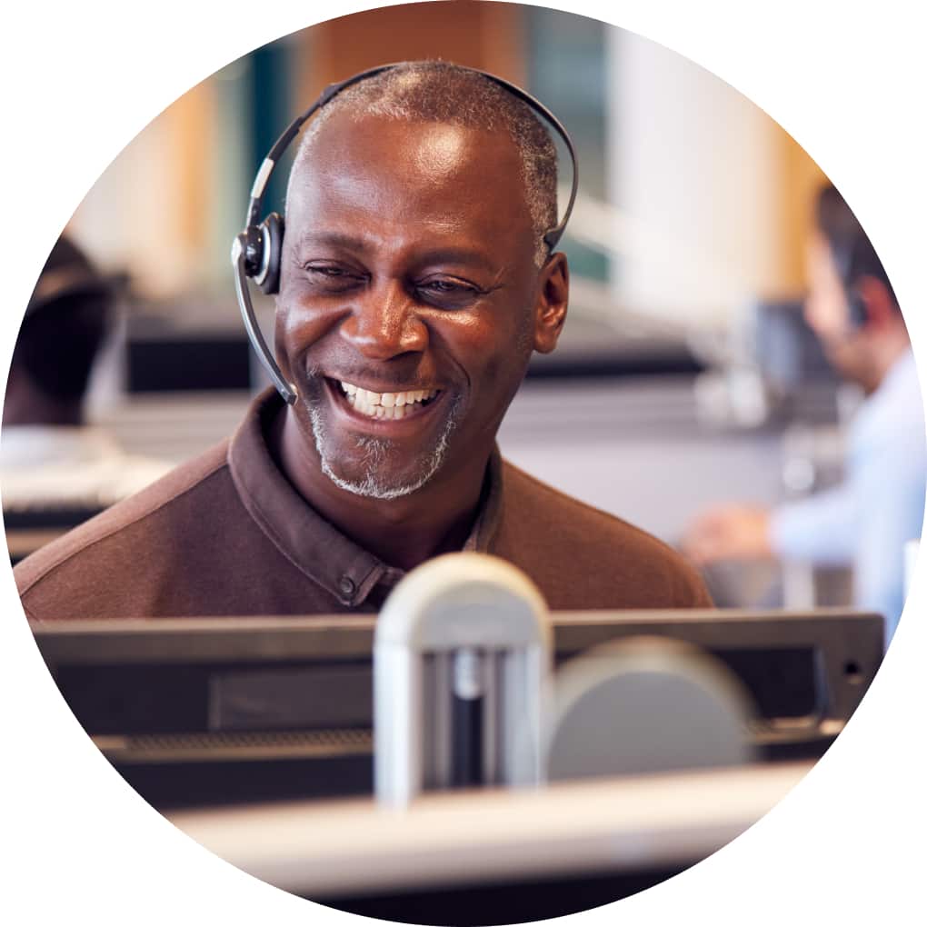 A customer support expert smiles while on a call with a client. 