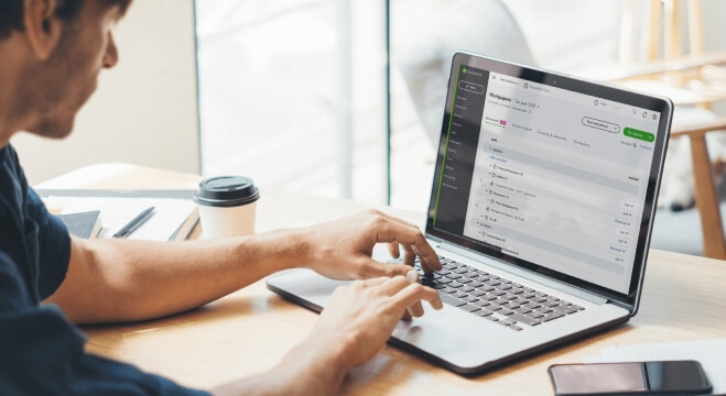 Man working his laptop with the QuickBooks Online Workpapers screen visible on the monitor