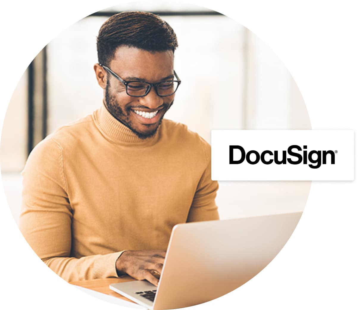 Smiling man in beige turtleneck typing at laptop, Docusign logo over top 