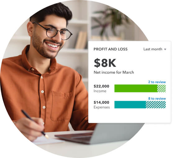 A smiling man wearing a terracotta shirt looks at Profit and loss in QuickBooks on his laptop.