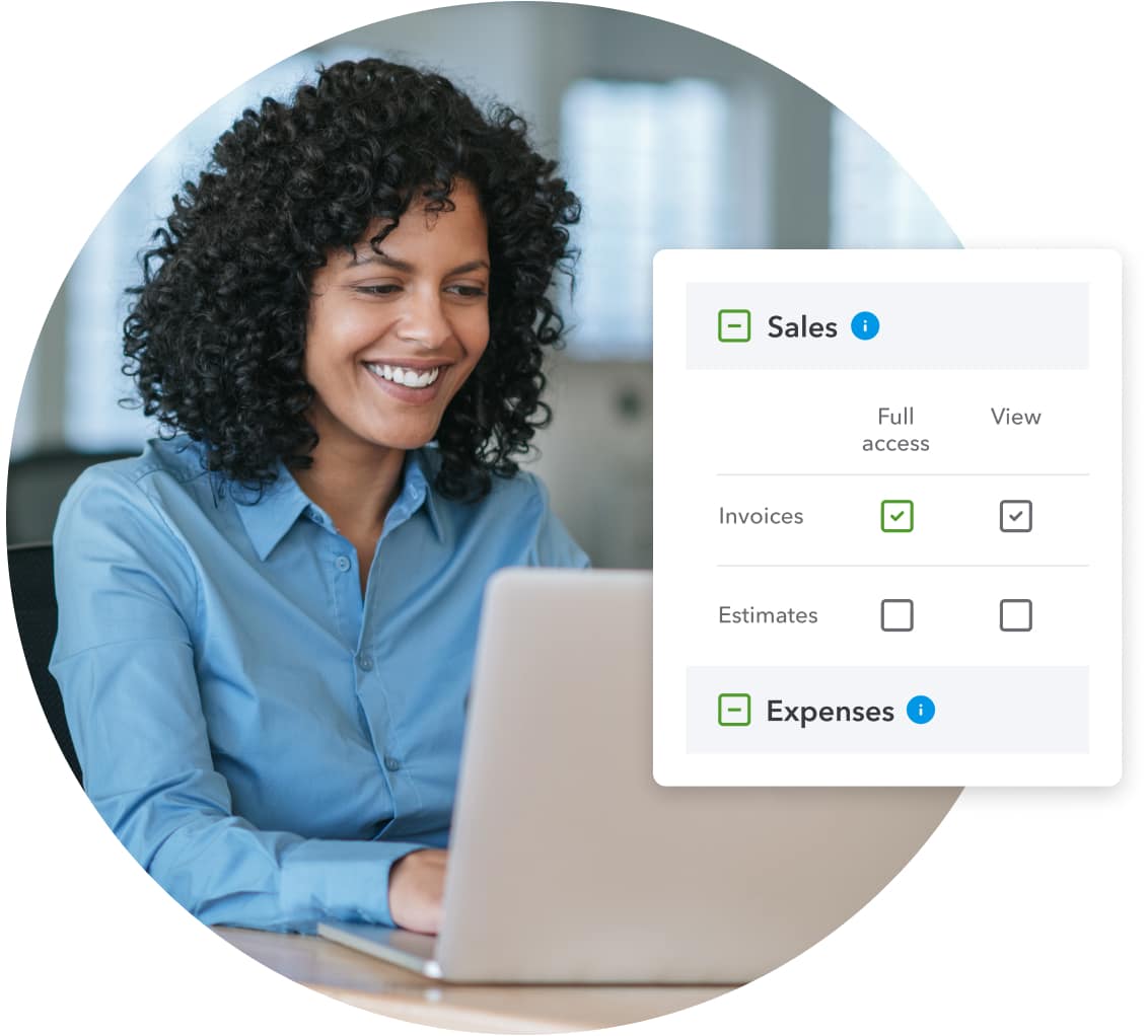 A smiling woman in a corporate office uses her laptop to set access in QuickBooks for the sales team