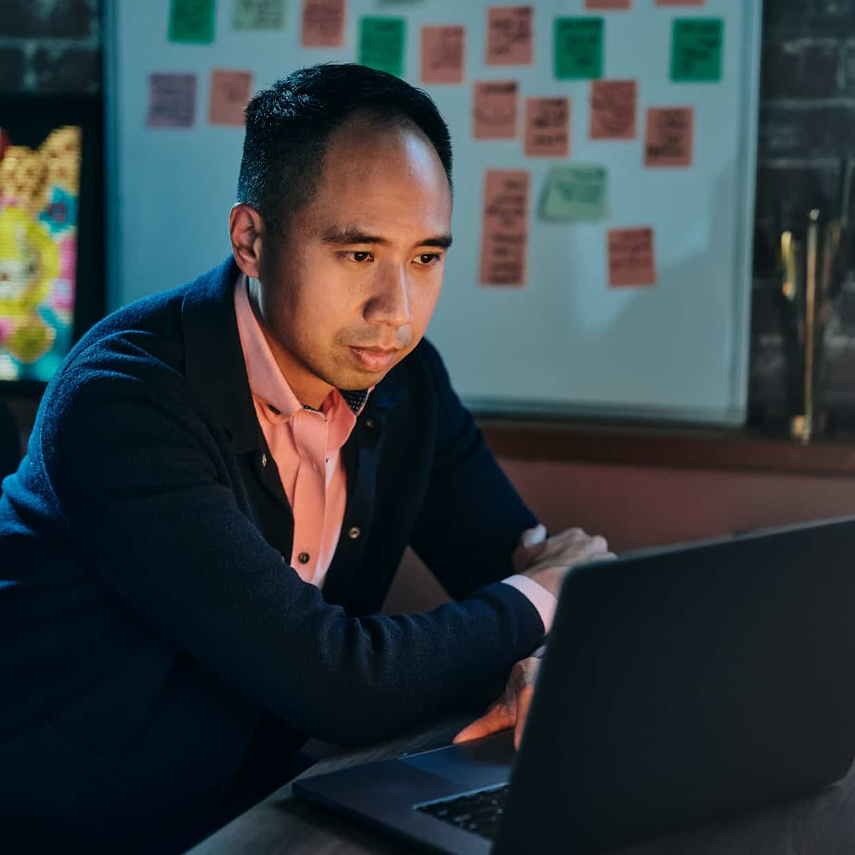 A man checks QuickBooks on his laptop in a darkly lit room