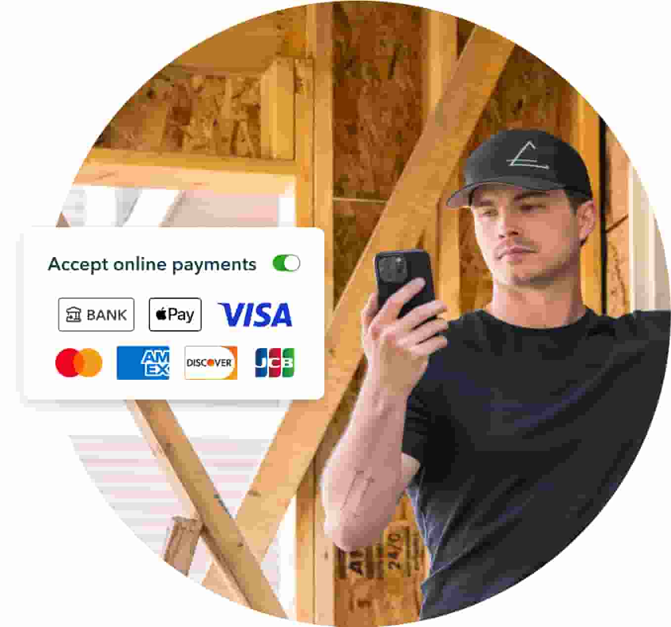 A renovation expert, standing in a house addition under construction, holds up his phone and activates accept online payment in QuickBooks Online.