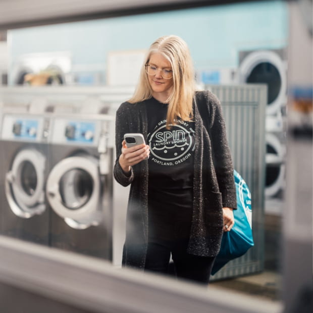A laundromat owner checks the QuickBooks app on her smart phone.