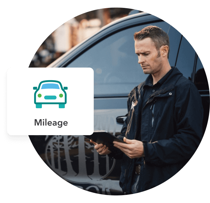 A worker leans up agains his truck and checks his mileage in QuickBooks Online