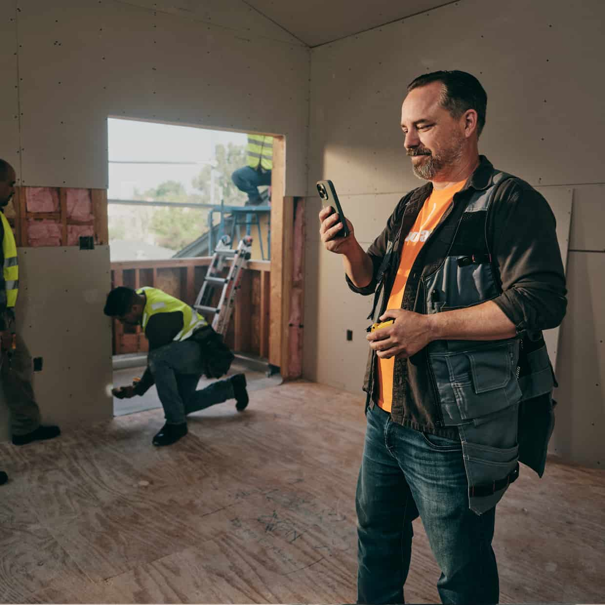 Modative owner Christian Navar, standing in a building under renovation, checks QuickBooks on his smart phone.