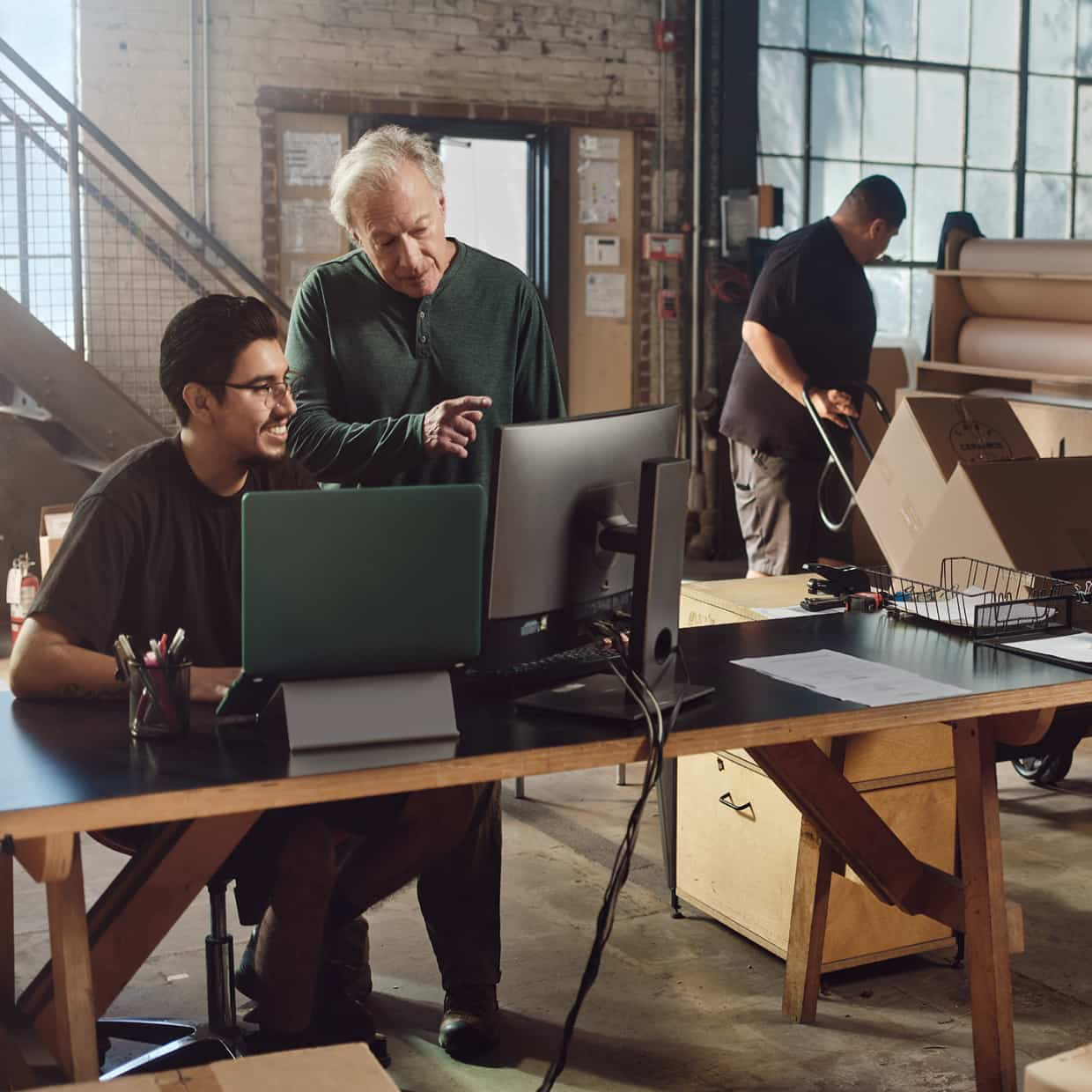 A group of people sitting around a table with laptops.