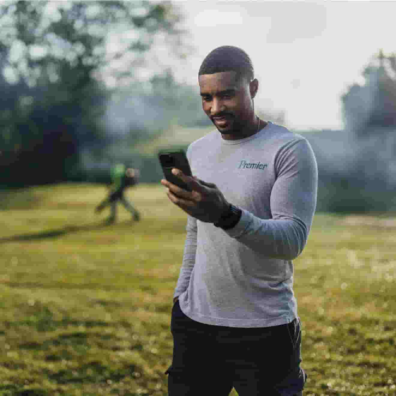 Premier professional landscaping owner checking mobile on the grass ground.