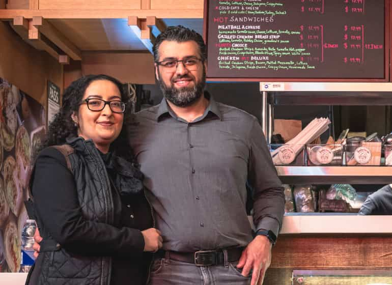 The owners of Grandma Loves You restaurant standing before the front counter.