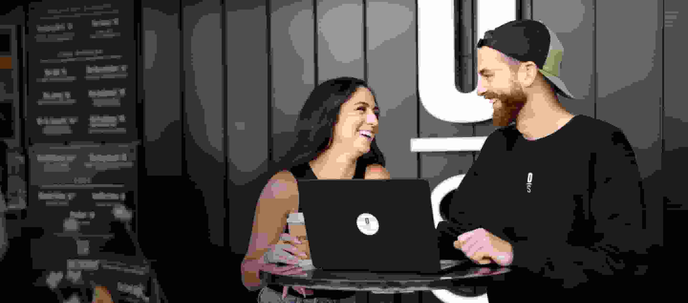 Man and woman smile with a laptop in front.