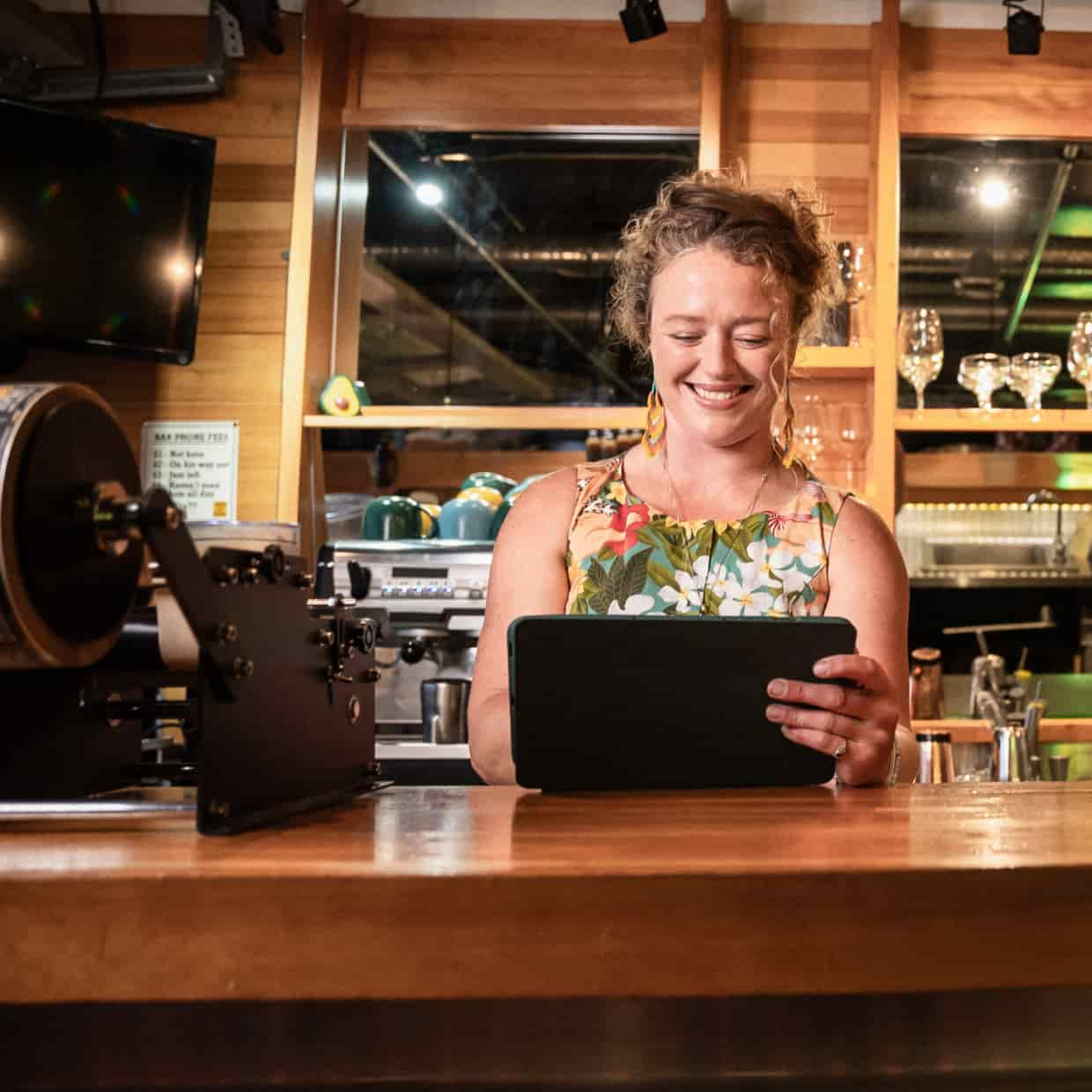 Restaurant owner woman stand in counter holding a tablet.