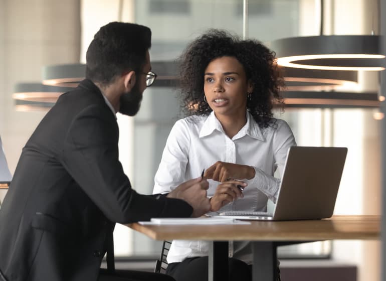 A sharply dressed consultant confers with a client in a spacious office setting. 