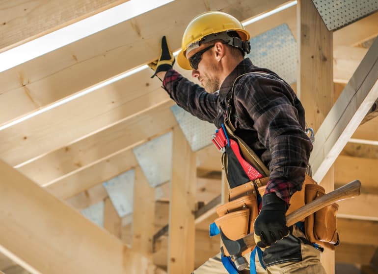 A construction worker walks on wood beams of a building under construction.