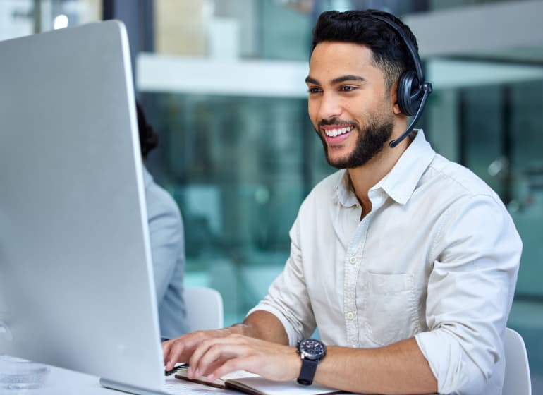 A smiling contractor in an office wearing a headset.