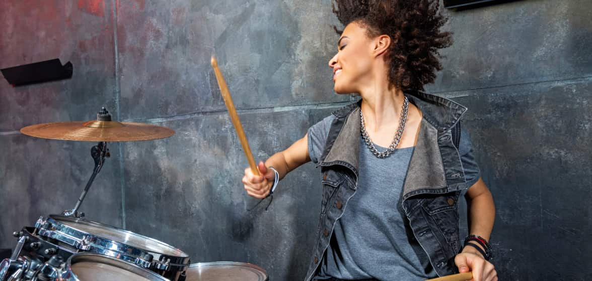 A woman flows with the beat while playing her drum set. 