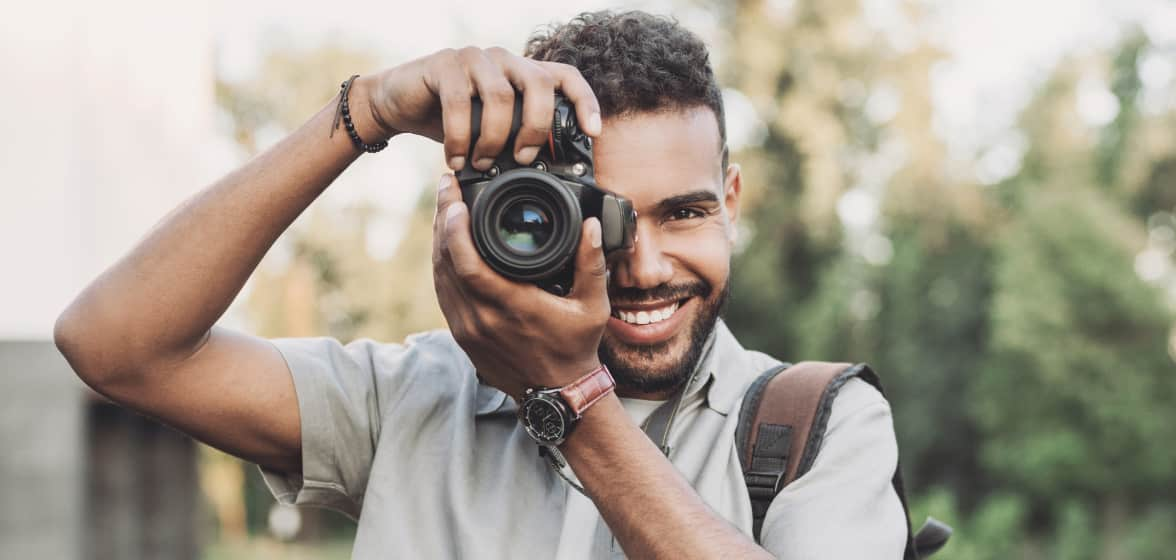 A photographer smiles while he aims his camera.