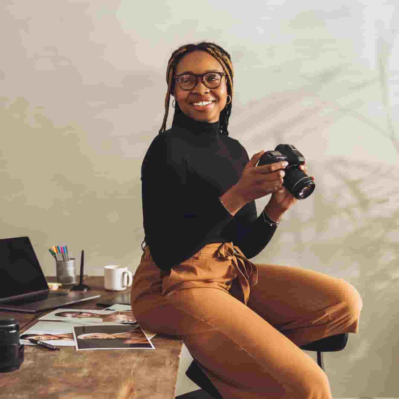 A photographer woman holding camera sit on tablet, smile with confidence. 