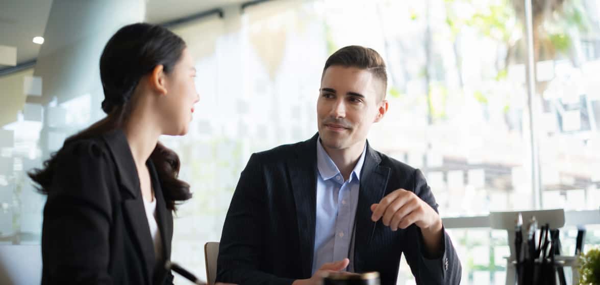 A woman and a man wearing business attire have a discussion.