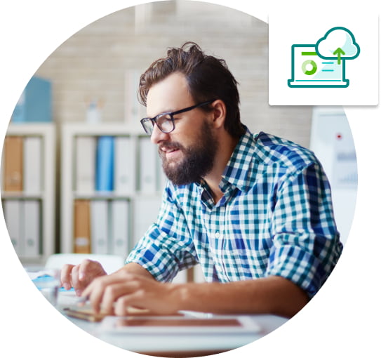 Bearded man in checkered shirt working intently on laptop computer.